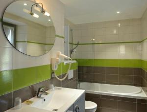 a bathroom with a sink and a mirror and a tub at Logis Hôtel Auberge de la Bonde in Langeais