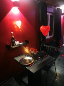 a red room with a table with a heart lamp and wine glasses at Loft d'amour in Ligné