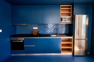 a kitchen with blue cabinets and a stainless steel refrigerator at Mid-Atlantic Boutique Hostel in Angra do Heroísmo