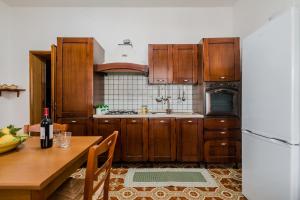a kitchen with wooden cabinets and a table and a refrigerator at Terre di mare near the sandy beach with pool, parking & wifi in Fontane Bianche