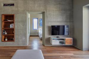 My Santorini Villa, Pyrgos Luxury في بيرغوس: غرفة معيشة مع تلفزيون بشاشة مسطحة على جدار