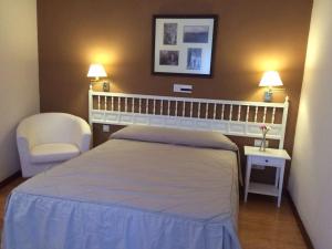 a bedroom with a bed and a chair and two lamps at Hotel Rural Mariblanca in Sacedón