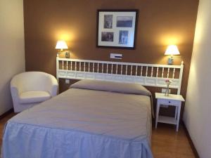 1 dormitorio con 1 cama, 1 silla y 2 lámparas en Hotel Rural Mariblanca, en Sacedón