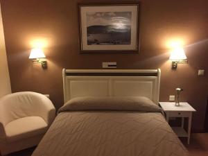 um quarto com uma cama e uma cadeira e duas luzes em Hotel Rural Mariblanca em Sacedón
