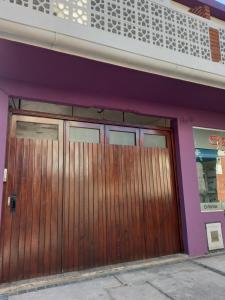 un par de puertas de madera en un edificio púrpura en Duplex en San Bernardo a dos cuadras de la playa en San Bernardo