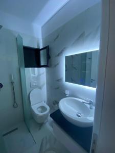 a bathroom with a sink and a toilet and a mirror at City Glow Apartments in Sarandë