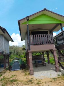 einen Pavillon mit einer Bank und einem Zelt neben einem Haus in der Unterkunft Dusun Rimbun Agro Farmstay in Kuala Kerai
