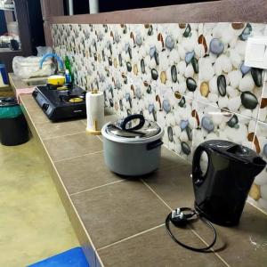 a kitchen counter with a pot and a wall of cups at Dusun Rimbun Agro Farmstay in Kuala Kerai