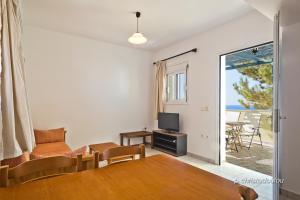 uma sala de estar com uma mesa de jantar e uma televisão em Albatros Studios & Apartments em Lefkos Karpathou