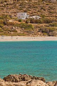 Blick auf einen Strand mit einem Haus im Hintergrund in der Unterkunft Albatros Studios & Apartments in Lefkos Karpathos