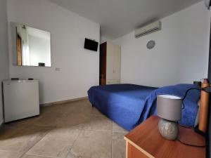 a bedroom with a blue bed and a table with a lamp at White Sand affittacamere in La Caletta