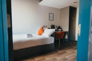 a bedroom with a bed with an orange pillow and a desk at Quarter by the Warren Collection in Belfast