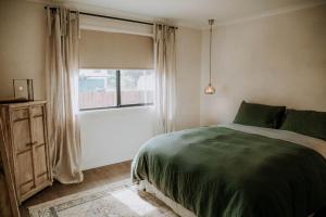 Un dormitorio con una cama verde y una ventana en Olive Grove Winton, en Winton