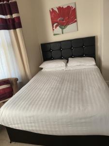 a bedroom with a large bed with a black headboard at Diamonds Lodge near York Hospital in York