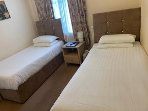 een slaapkamer met 2 bedden en een tafel met een nachtkastje bij Diamonds Lodge near York Hospital in York
