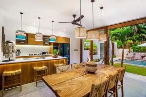 cocina abierta y comedor con mesa de madera en La Jungle Villa, en Ubud