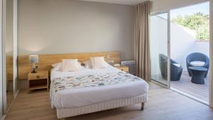 a bedroom with a bed and a sliding glass door at Hôtel Les Grenettes in Sainte-Marie-de-Ré