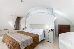 a white bedroom with a bed and a white dresser at Hotel La Terra in Ostuni