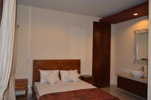 a bedroom with a bed with a mirror and a sink at Shreya Guest House in Ubud