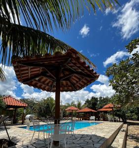 um guarda-sol e cadeiras junto a uma piscina em Pousada Encanto dos Anjos em Pirenópolis