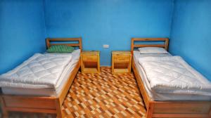 2 camas individuales en una habitación con paredes azules en The Swiss Side Iten en Iten
