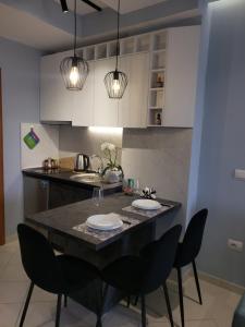 a kitchen with a black table with chairs and lights at Appartamento Nr. 28. Centrale e luminoso in Shkodër