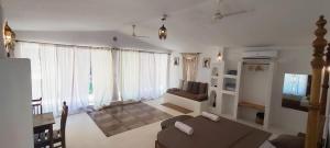 a living room with a couch and a tv at Rooms in Greek Jungle Villa, Thalassa Road in Siolim