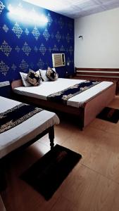 1 dormitorio con 2 camas y pared azul en Hotel Majors Den, en Nueva Delhi