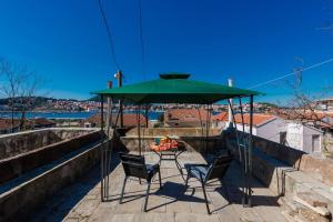 two chairs and a green umbrella on a patio at Apartment Mia in Dubrovnik