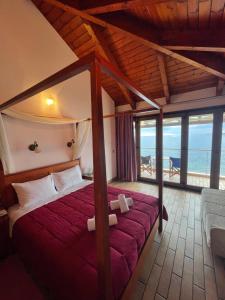 a bedroom with a canopy bed with a view of the ocean at Entheon Rooms in Marathopoli