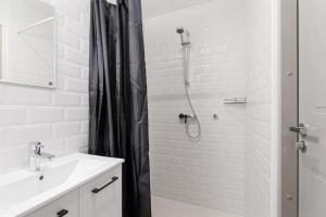 een witte badkamer met een douche en een wastafel bij City Center Studio Apartment in Tallinn