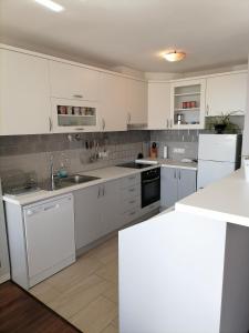 een witte keuken met witte kasten en apparaten bij Apartman Nela in Omiš