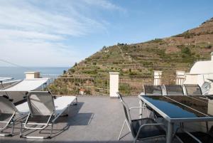 a patio with tables and chairs and a hill at Luxury Seaview Apartments Manarola by Arbaspàa in Manarola
