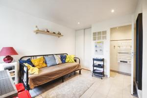 a living room with a couch with yellow and blue pillows at Studio calme proche Paris avec terrasse privative et jacuzzi en option in Palaiseau