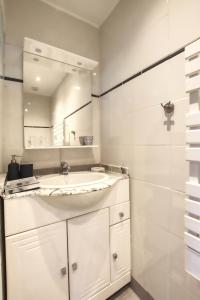 a white bathroom with a sink and a mirror at Studio calme proche Paris avec terrasse privative et jacuzzi en option in Palaiseau