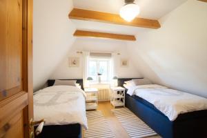 two beds in a attic room with a window at Reetdachhaus Isemann in Nebel