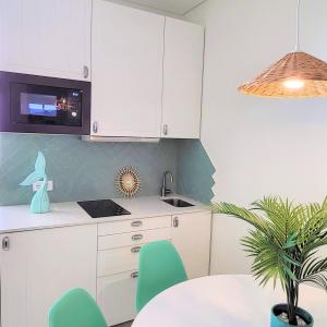 a kitchen with white cabinets and a table and a plant at The Shore @ Surf Paradise - Patio Terrasse in Espinho