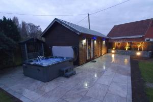 un patio trasero con bañera de hidromasaje y una casa en The Lodge en Guyhirn