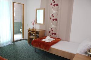 a bedroom with a bed and a desk and a mirror at Pansion Nikica Kozina in Međugorje