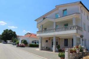 a white building with a balcony on a street at Pansion Nikica Kozina in Međugorje