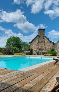 uma piscina com um deque de madeira e um edifício em Le Mas de Rigoulac chambre BULLE SPA sur réservation em Bouyssounouse