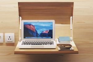 a laptop computer sitting on top of a wooden desk at My Studio Hotel Juanda Airport Surabaya in Sedati