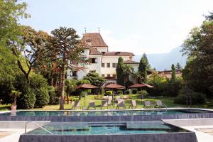 a resort with a pool and chairs and a building at Hotel Castel Rundegg (Adults Only) in Merano