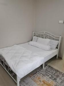 1 cama con marco metálico y sábanas blancas en Homestay Qaseh Kerteh, en Kertih