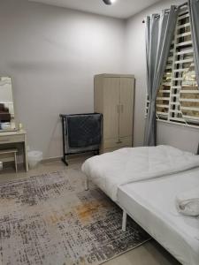 a bedroom with a bed and a desk and a window at Homestay Qaseh Kerteh in Kertih