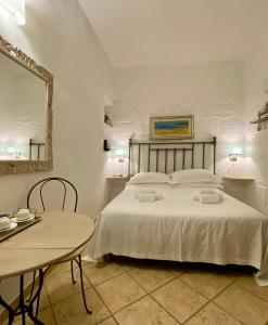 een slaapkamer met een bed met een tafel en een spiegel bij Santo Stefano Home & Breakfast in Polignano a Mare