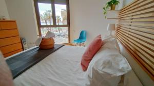 a bedroom with a large bed and a blue chair at Sunbeach Malagueta in Málaga