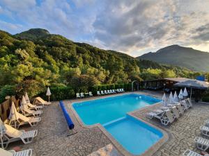 una piscina con tumbonas y una montaña en Family Hotel Enica, en Teteven