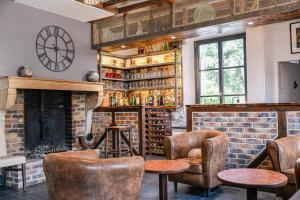 eine Bar mit Stühlen, einem Kamin und einer Uhr in der Unterkunft Logis Hostellerie la Chaumière in Arsonval