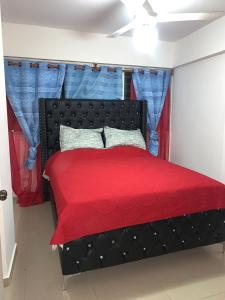 um quarto com uma cama preta e um cobertor vermelho em Apartamento en BOCA CHICA, a 50 metros, playa boca chica em Boca Chica